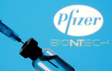 Frasco e seringa em frente aos logos da Pfizer e da BioNTech em foto de ilustração