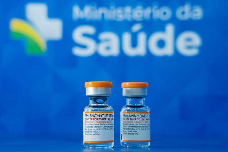 Imagem mostra duas unidades da vacina Pfizer para crianças com o logo do Ministério da Saúde atrás