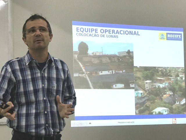 Cassio é um homem branco com cabelos grisalhos, ele veste uma camisa xadrez cinza