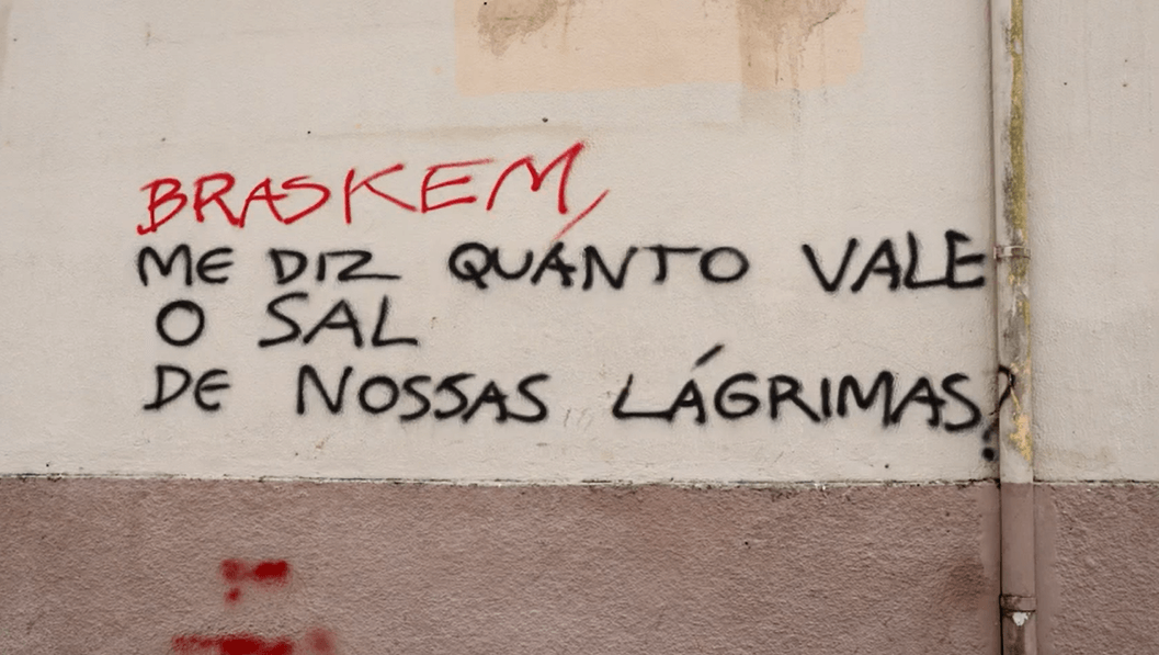 Grafite em muro de edifício afetado pela mineração da Braskem cobra a empresa por seus impactos emocionais, sociais e ambientais