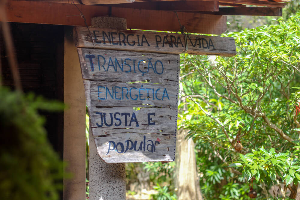 Placa de madeira pendura com a frase "energia para vida, transição energética justa e popular"